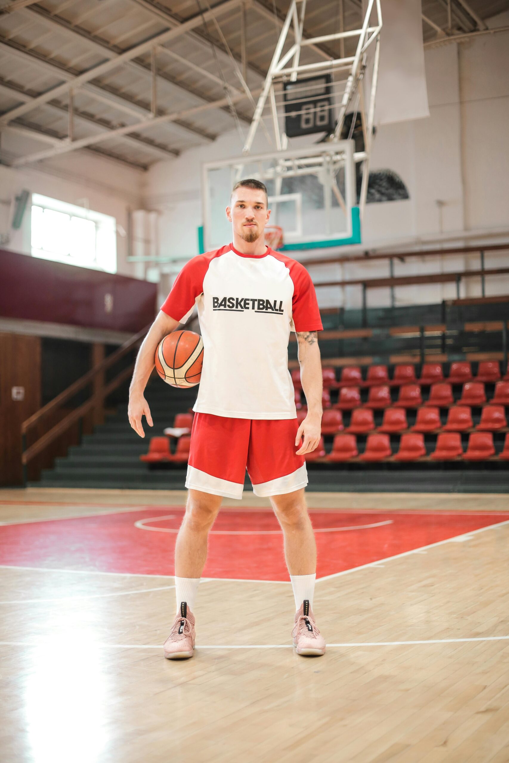 A basketball player poses on an indoor court, ready for practice or game.